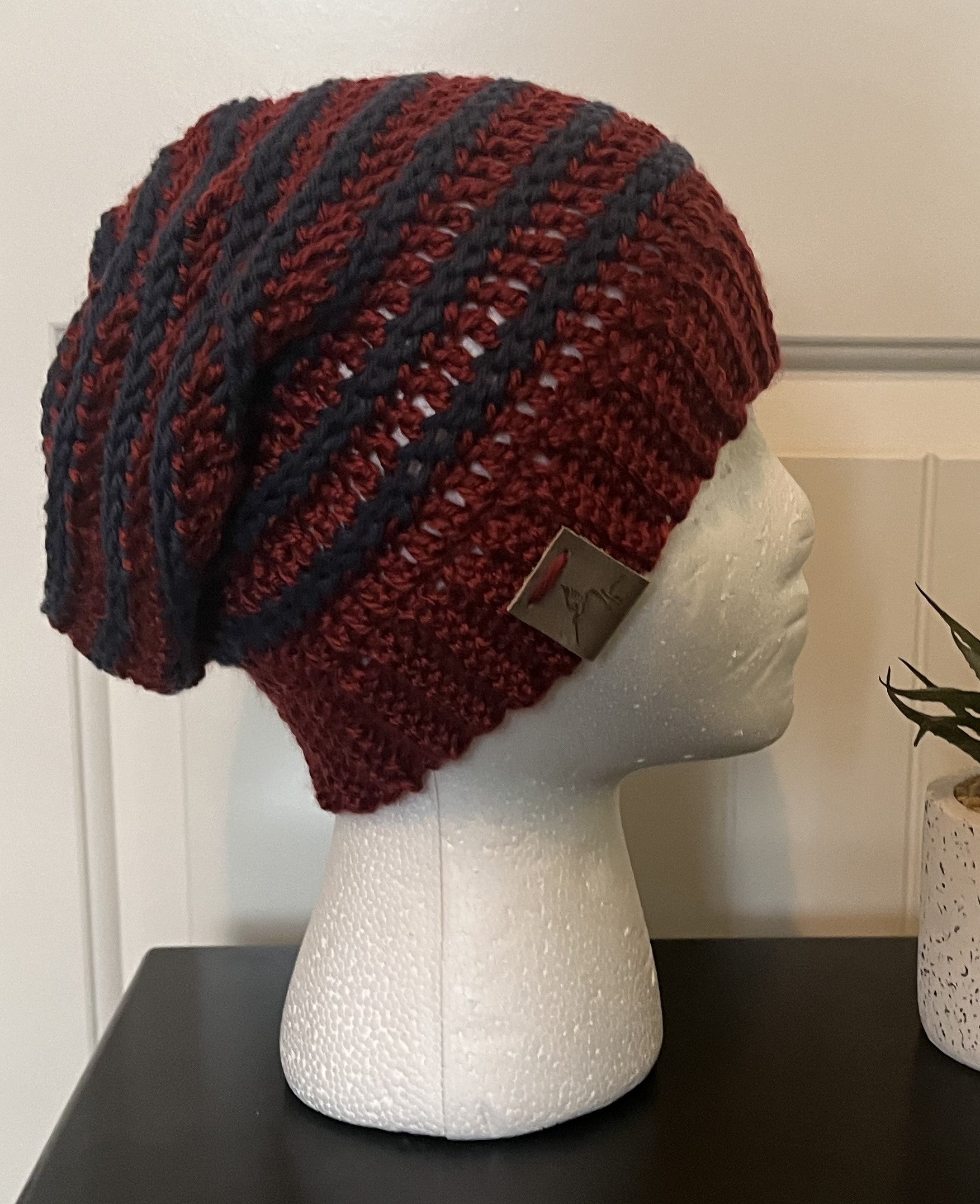 Knitted beanie with red and black stripes on a mannequin head against a neutral background