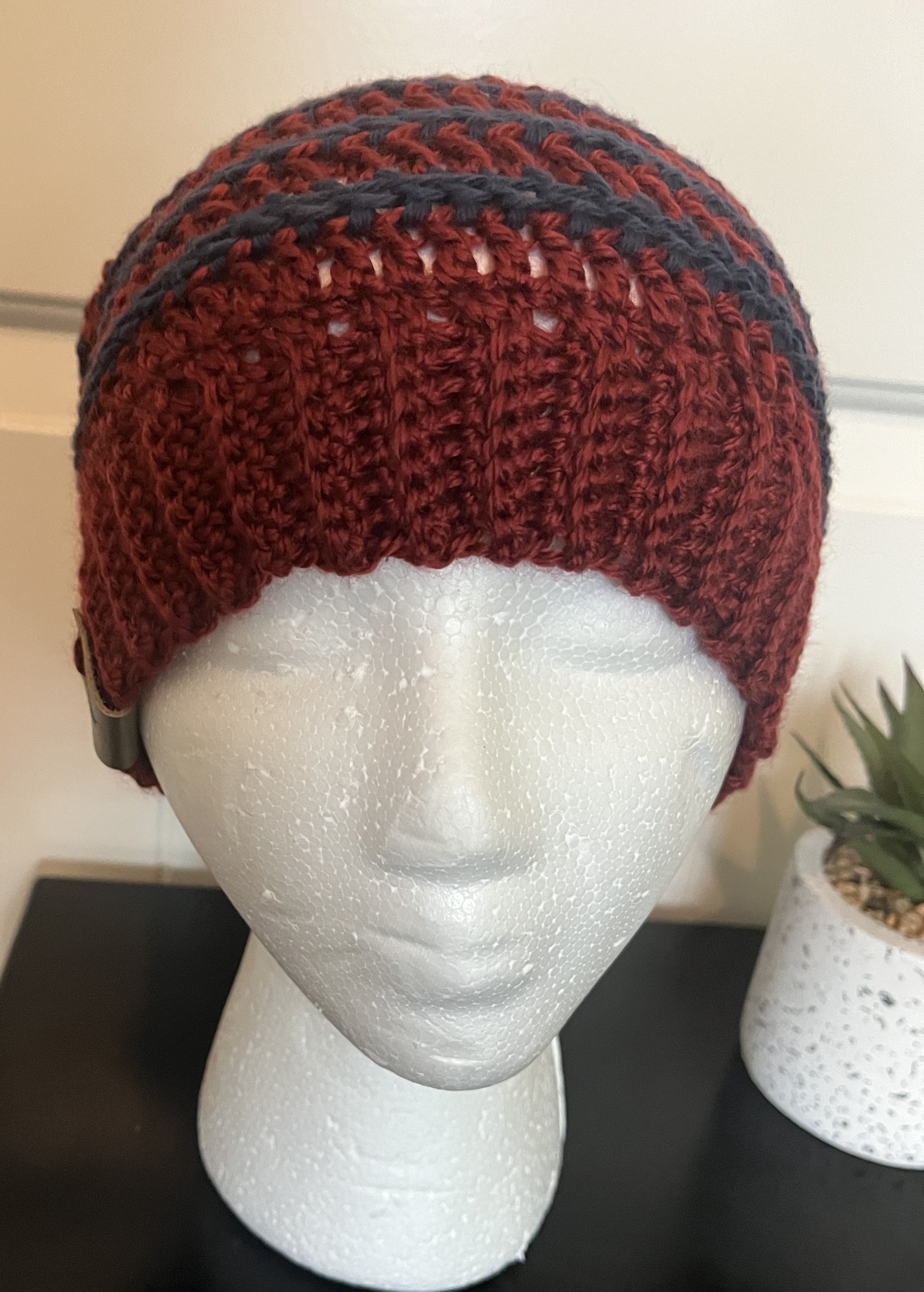 Red and black knitted beanie on a mannequin head with a white background