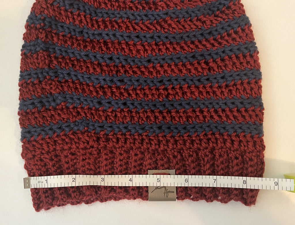 Knitted fabric with a striped pattern in red and blue, measured by a ruler on a white background.