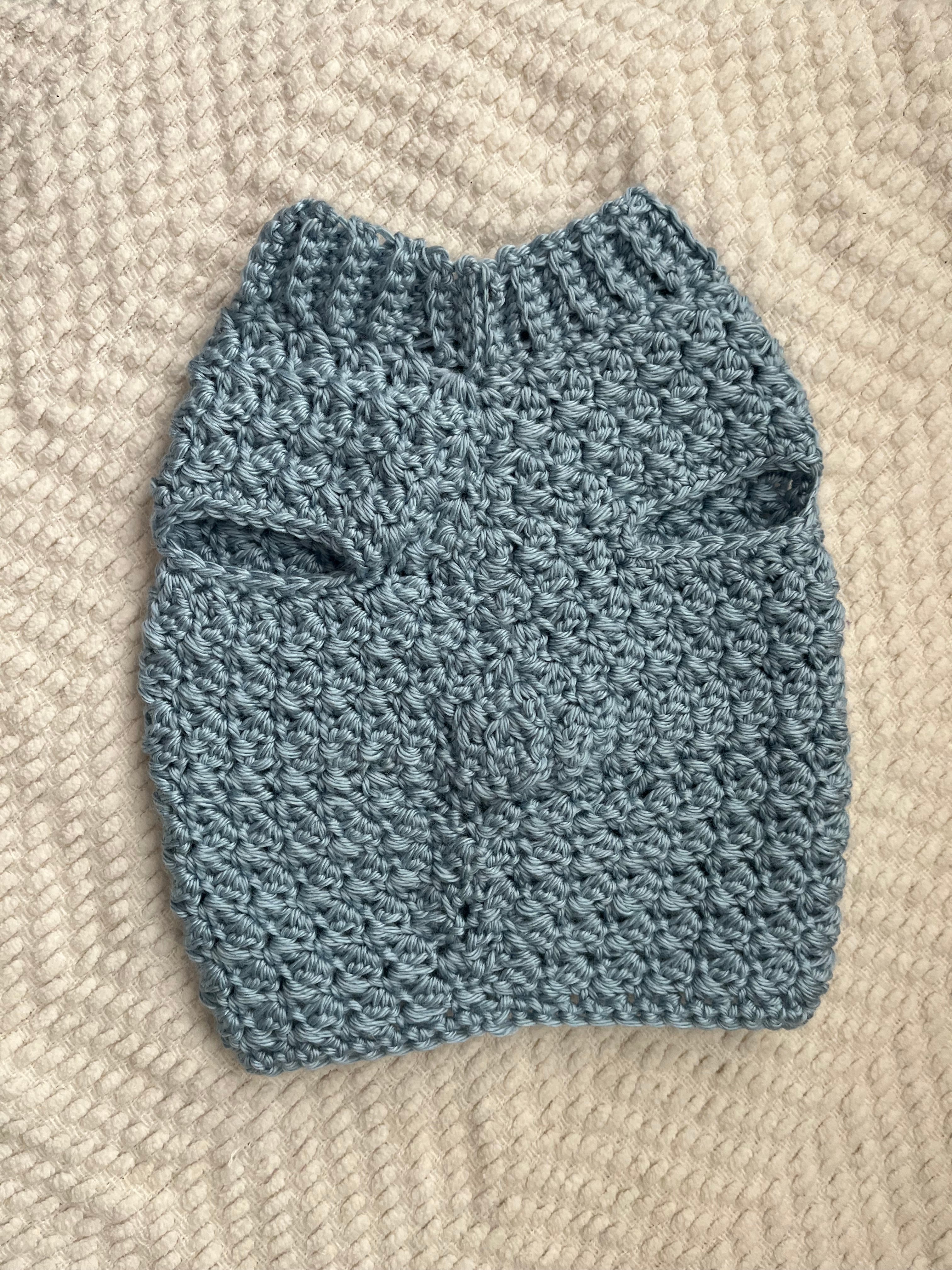 Blue knitted baby sweater on a beige textured surface