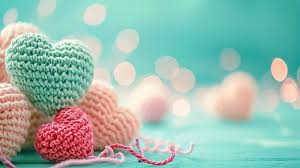 Knitted heart-shaped toys on a teal background with bokeh lights
